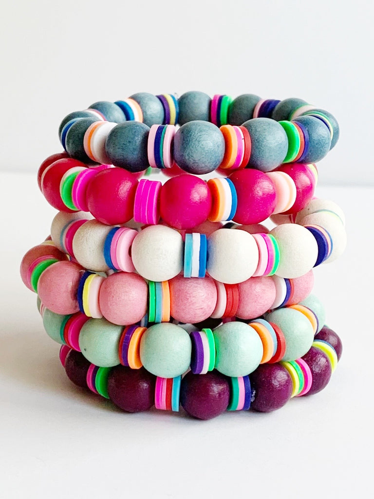 Children's White and Rainbow Confetti Stretch Bracelets in Blue, Bubble Gum Pink, Lipstick Pink, Sea Foam, White, and Plum stacked together.