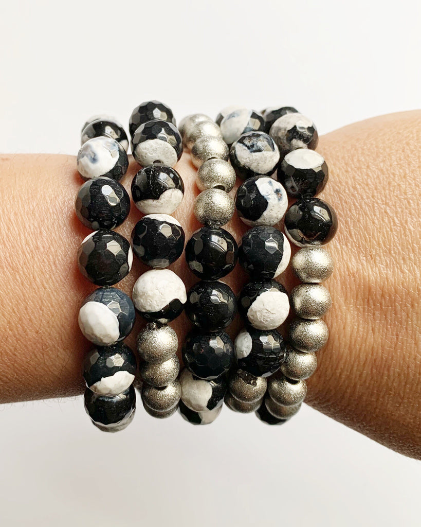 Women's wrist wearing five Black and White Agate with Silver Stacking Beaded Stretch Bracelets.