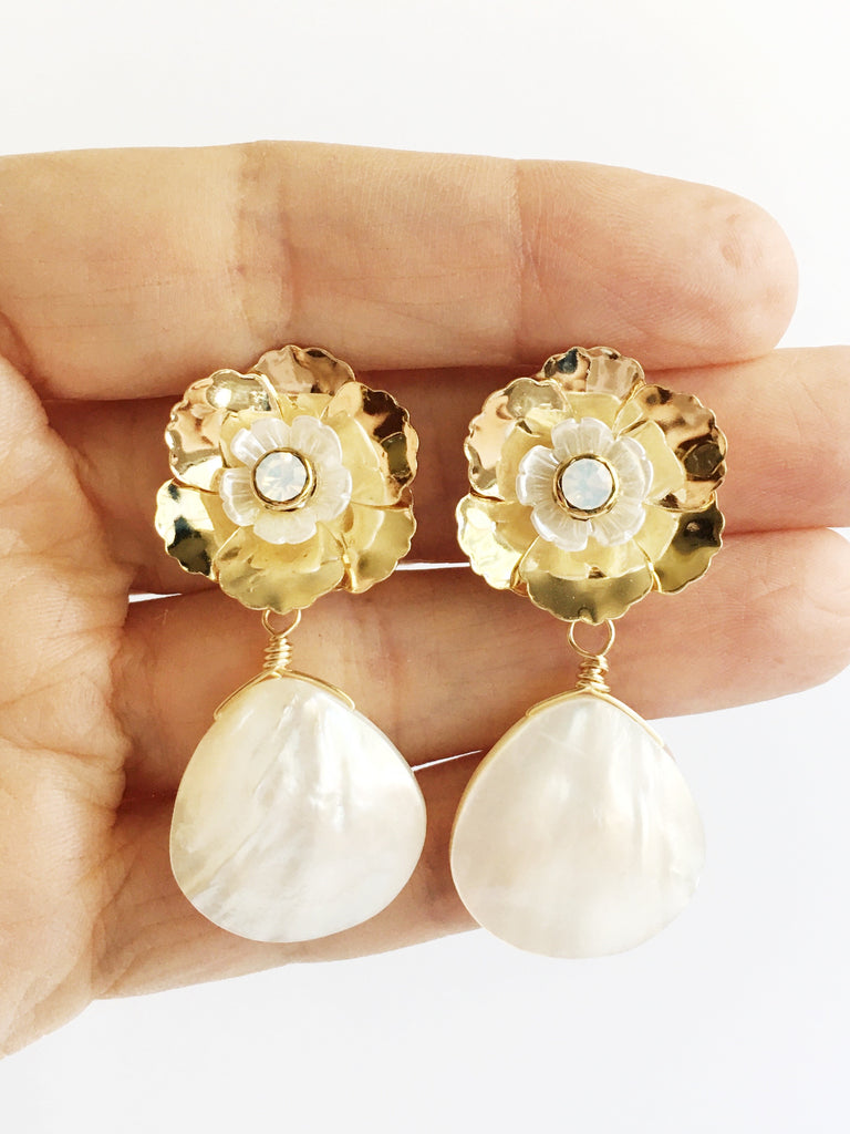 Hand holding Gold and white flower with mother of pearl teardrop dangle earrings.