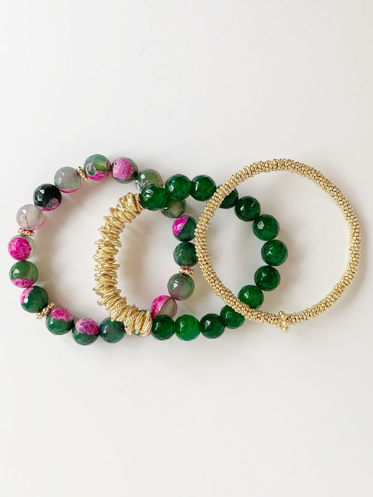 over lapping on table, Three beaded bracelets, one of small gold confetti, one of green agate beads, and one green and pink agate beads.