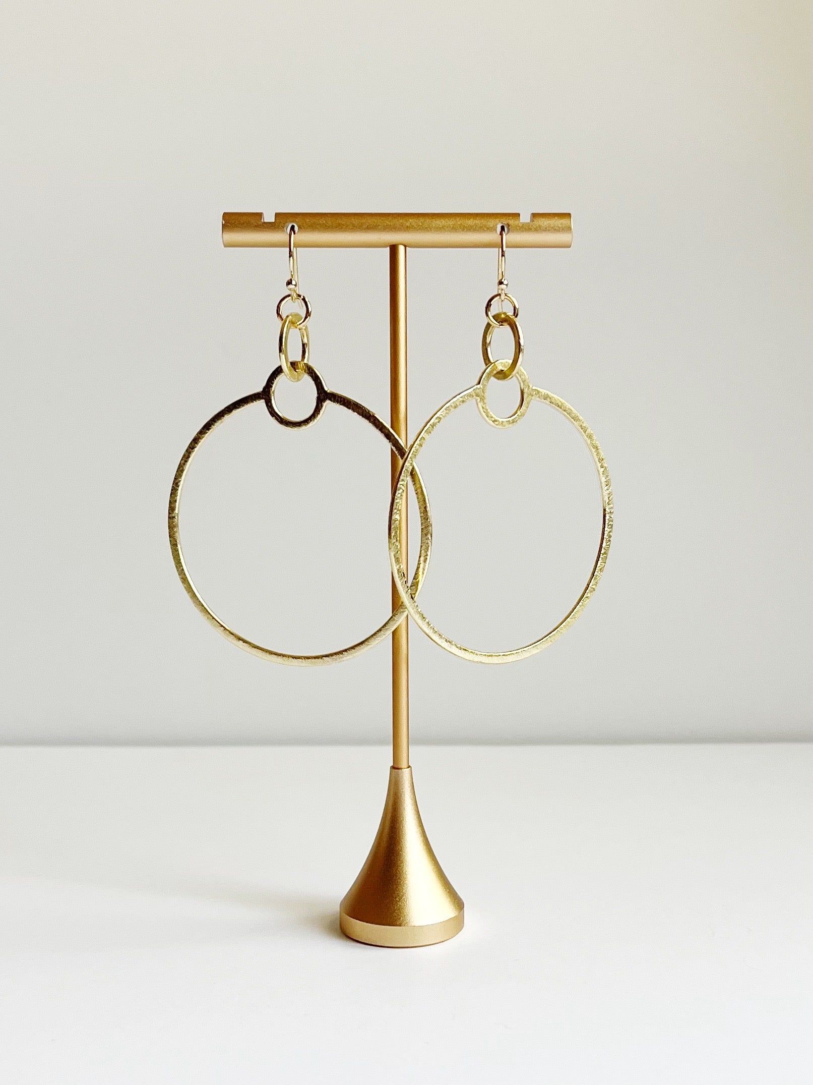 gold statement earrings displayed on t stand 
