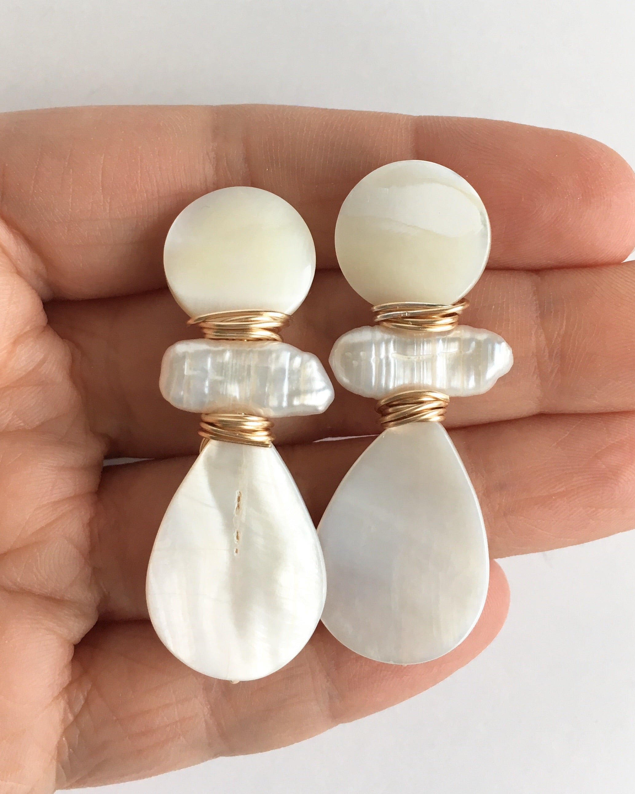Three Stone Mother of Pearl and Pearl Teardrop Earrings displayed on hand