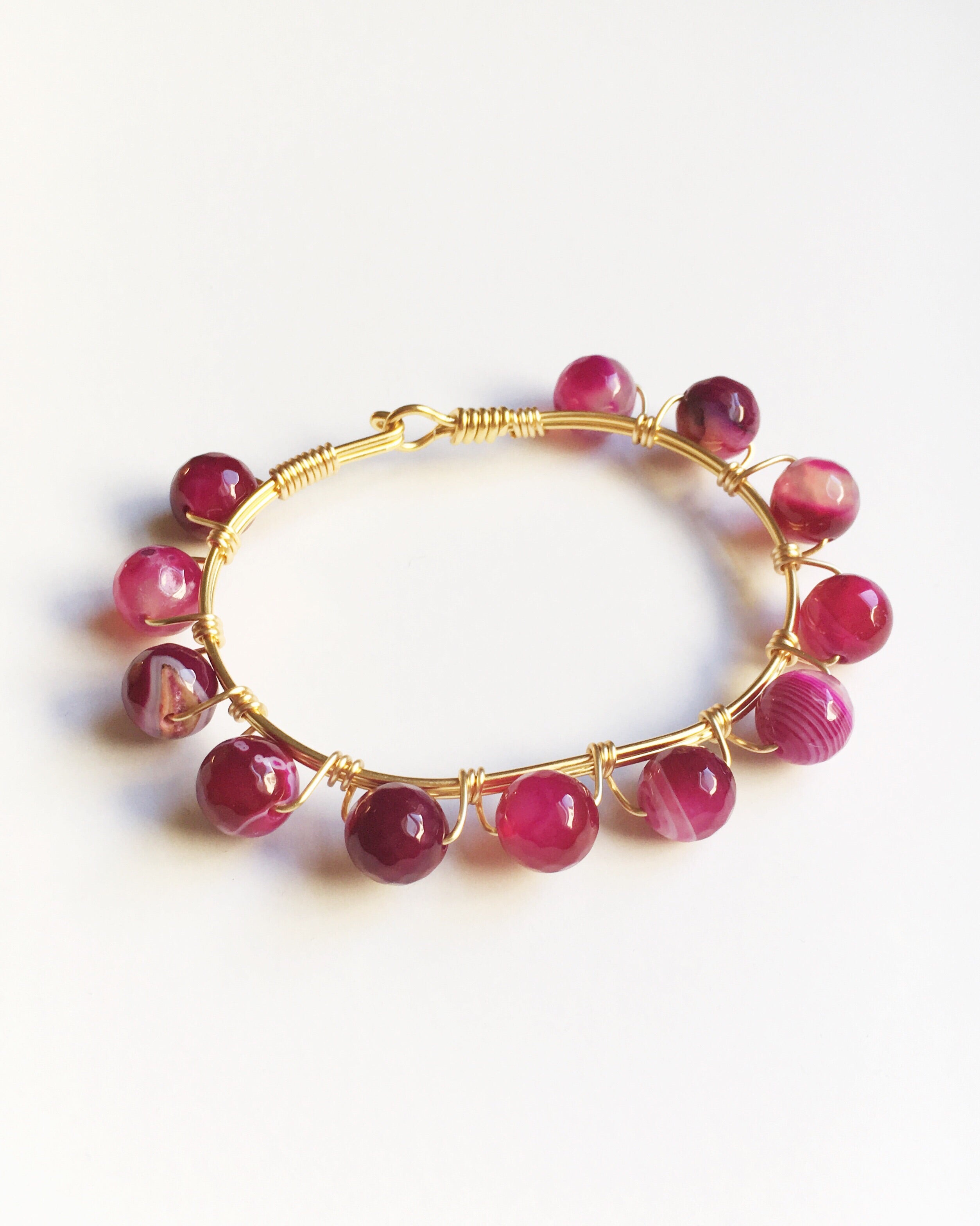 pink agate gemstone and gold bangle bracelet.