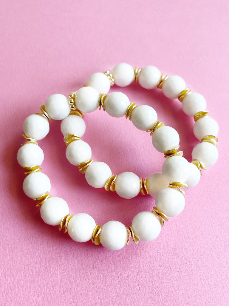 two white jade and yellow gold beaded bracelets on pink background
