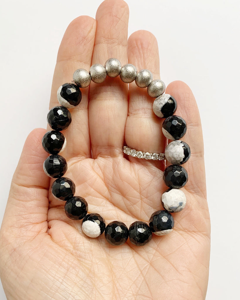 Hand, palm up, holding Black and White Agate with Silver Stacking Beaded Stretch Bracelet
