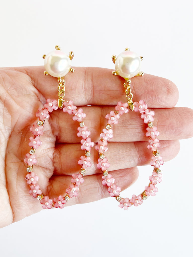 Hand holding Pink glass flower and pearl long earrings