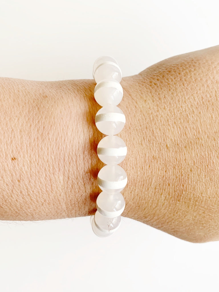 Hand strung bracelet with agate and sterling silver beads on stretch material on women's wrist.