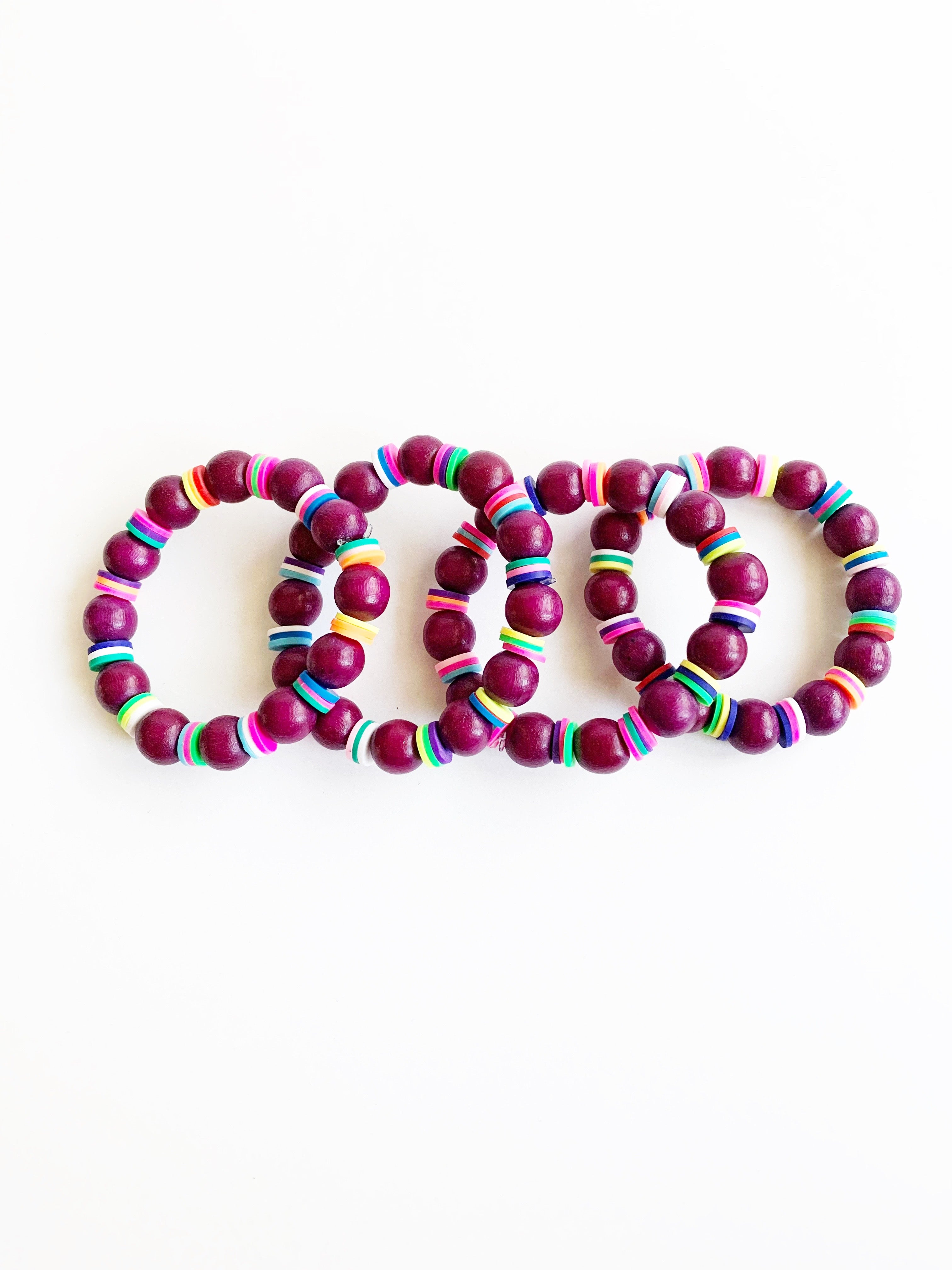 Four Child sized Plum and rainbow confetti beaded stretch bracelets overlaying each other.