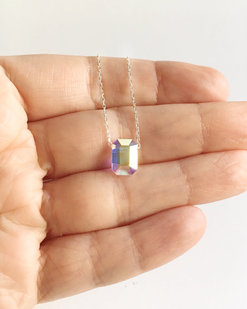 Small Aurora Borealis Crystal and Sterling Silver Pendant Necklace draped over fingers.
