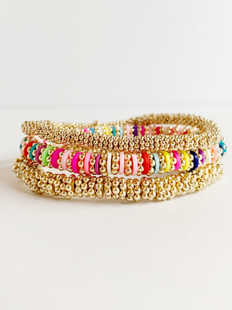 one small gold confetti bracelet, one medium gold confetti bracelet and one rainbow and gold confetti bracelet stacked on top of each other