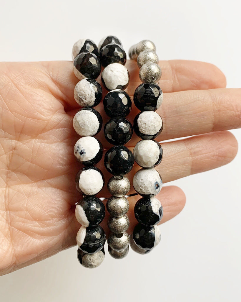 Fingers holding three Black and White Agate with Silver Stacking Beaded Stretch Bracelets