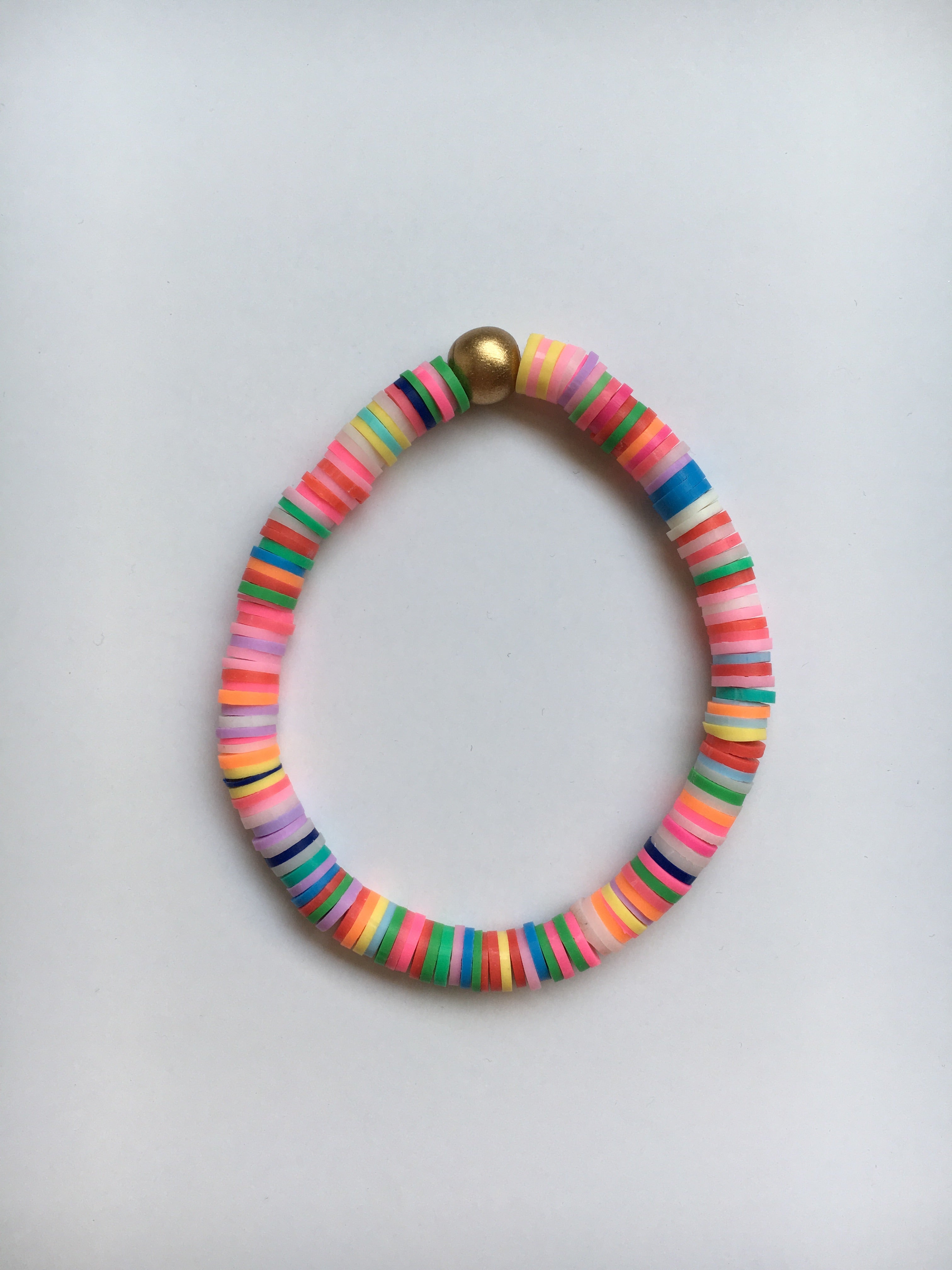 One Rainbow Confetti vinyl and wood Beaded Bracelet laying on table