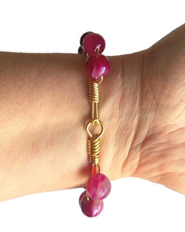Women's wrist wearing pink agate gemstone and gold bangle bracelet showing hook n eye clasp