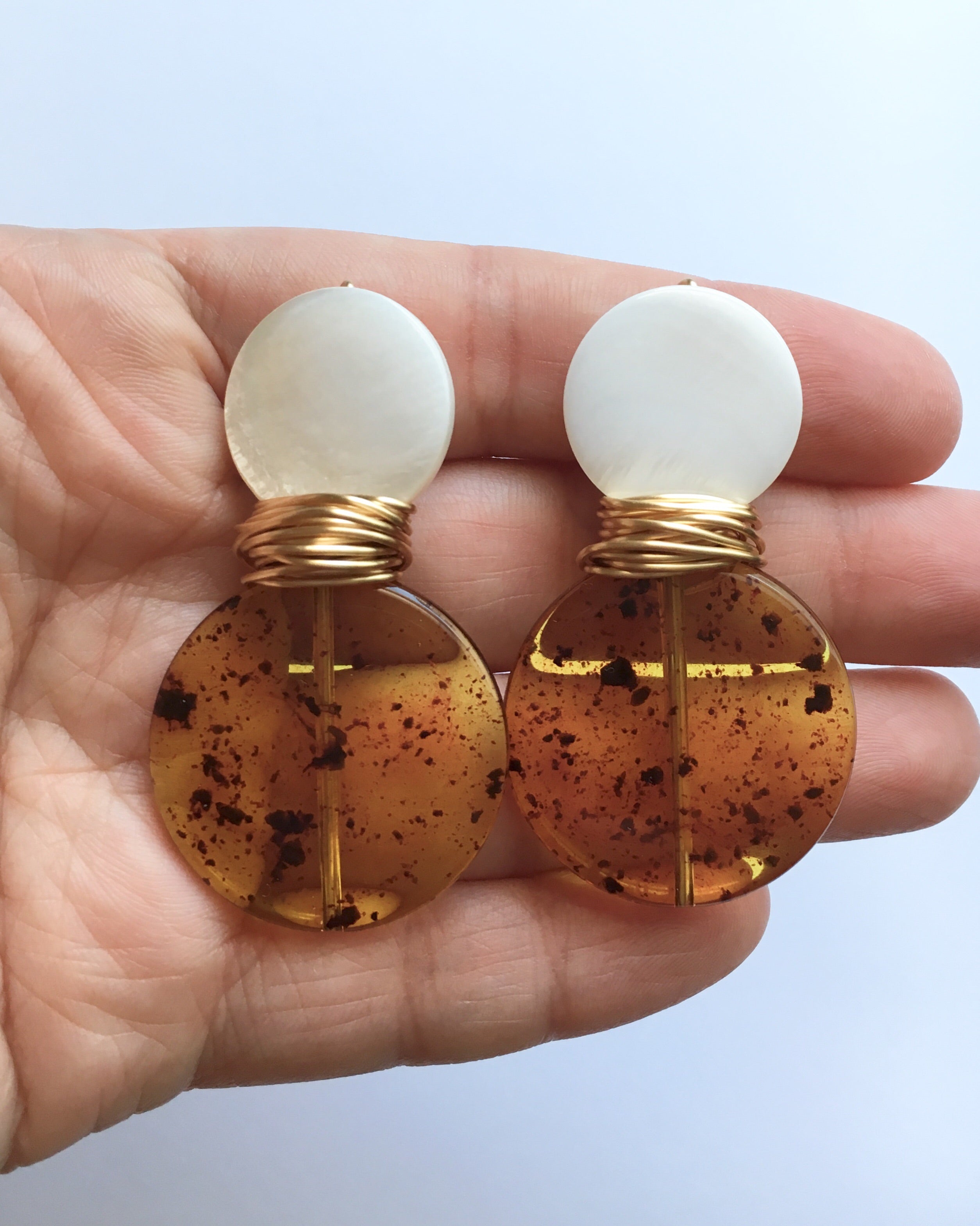 Hand holding Mother of Pearl and Tortoise Shell Wire Wrapped Earrings