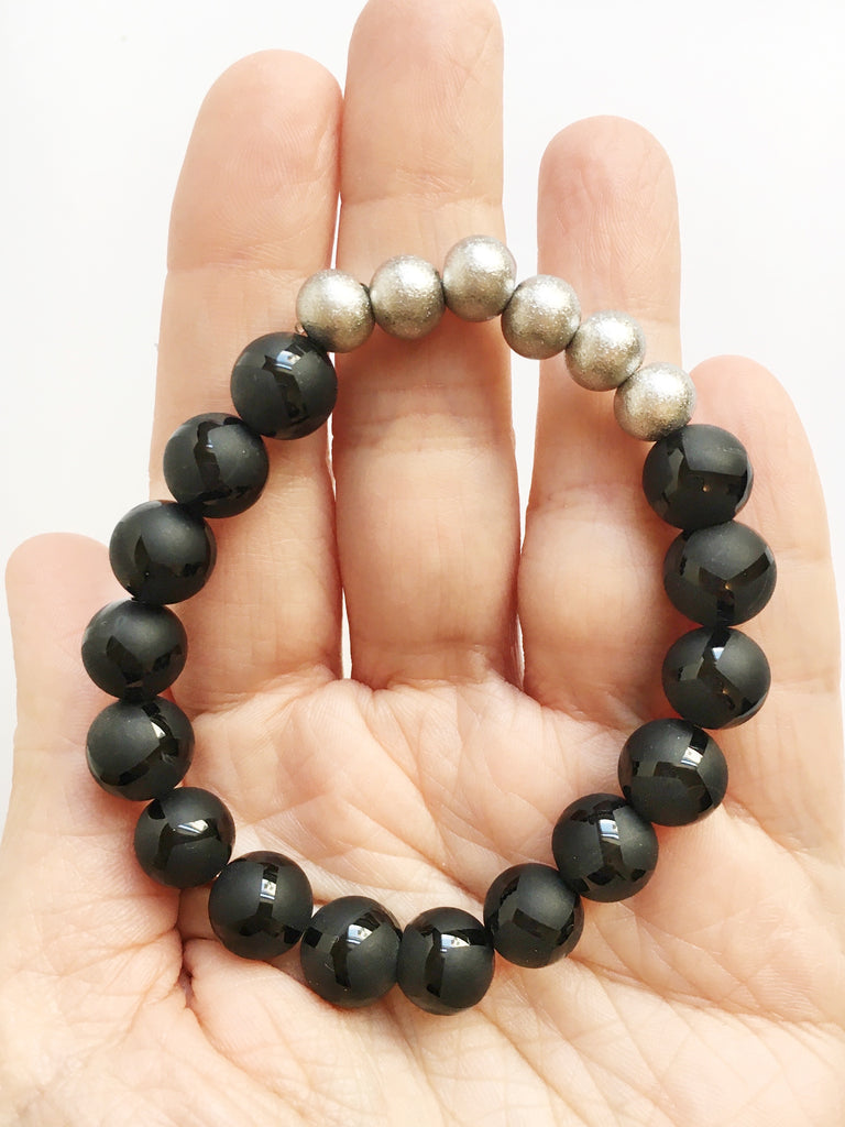 Hand, palm up holding Black Giraffe Agate and Stardust Stainless Steel Beaded Stretch Bracelet.