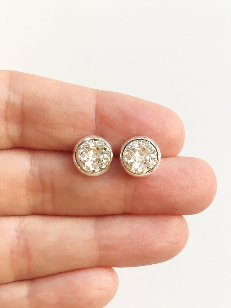 Hand holding Silver resin druzy stone stud earring set in a stainless steel setting between fingers.