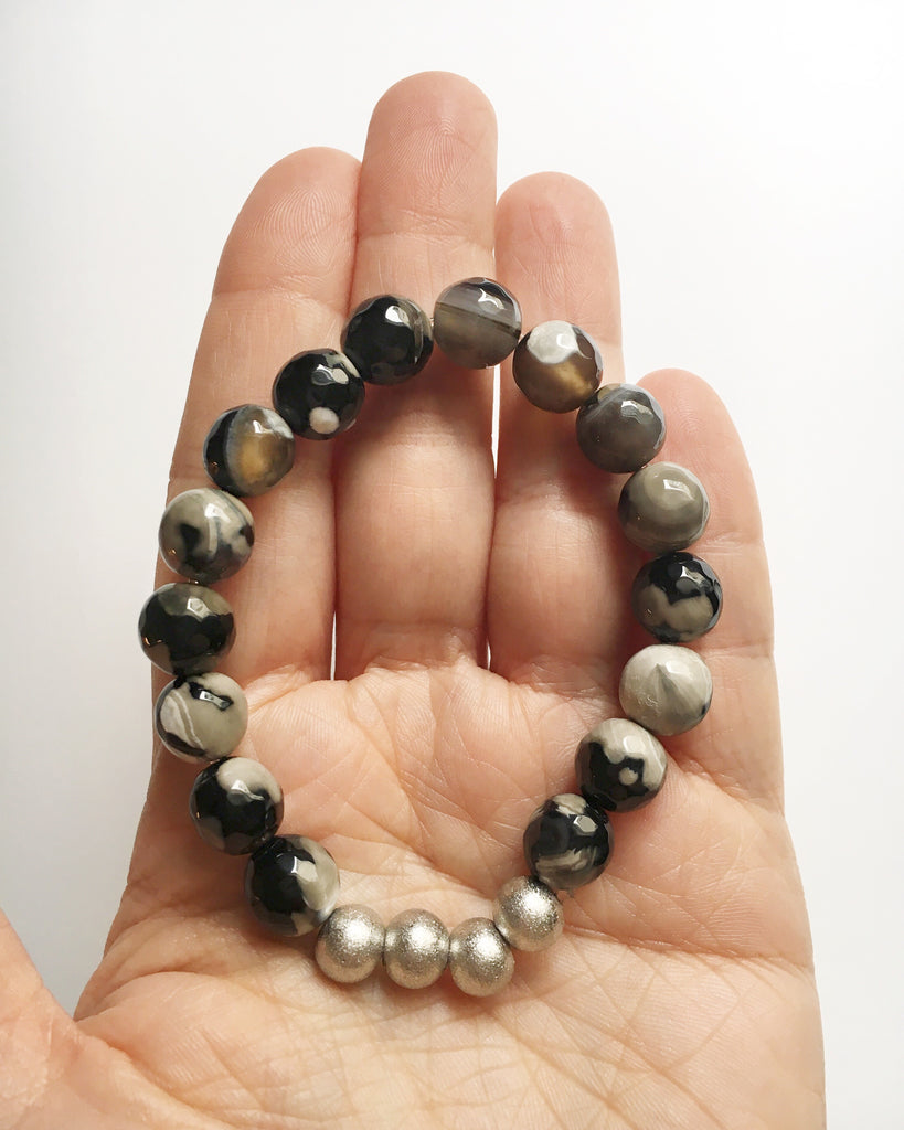 Palm of hand holding Black and Gray Agate with Silver Stacking Beaded Stretch Bracelet