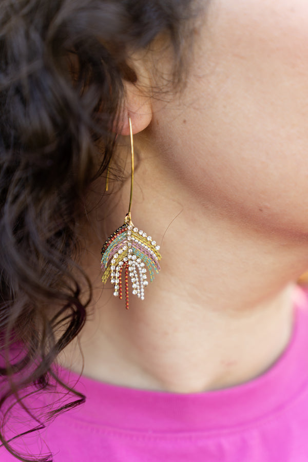 Gold drop dangle peacock colored earrings modeled on ear