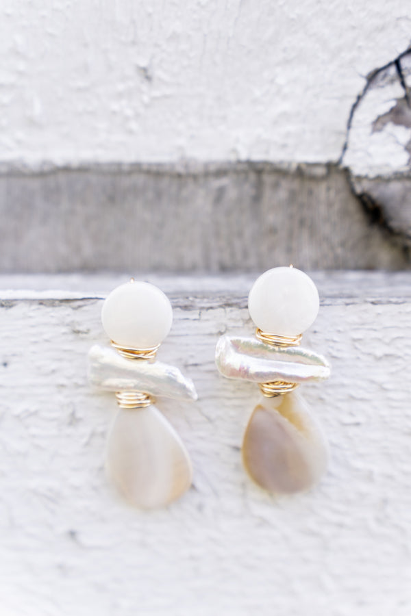 mother of pearl and stick pearl wire wrapped earrings with gold accents displayed on wood