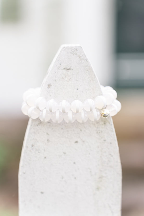 Two strands of white striped agate bracelets displayed on fence. ver beads on stretch material.