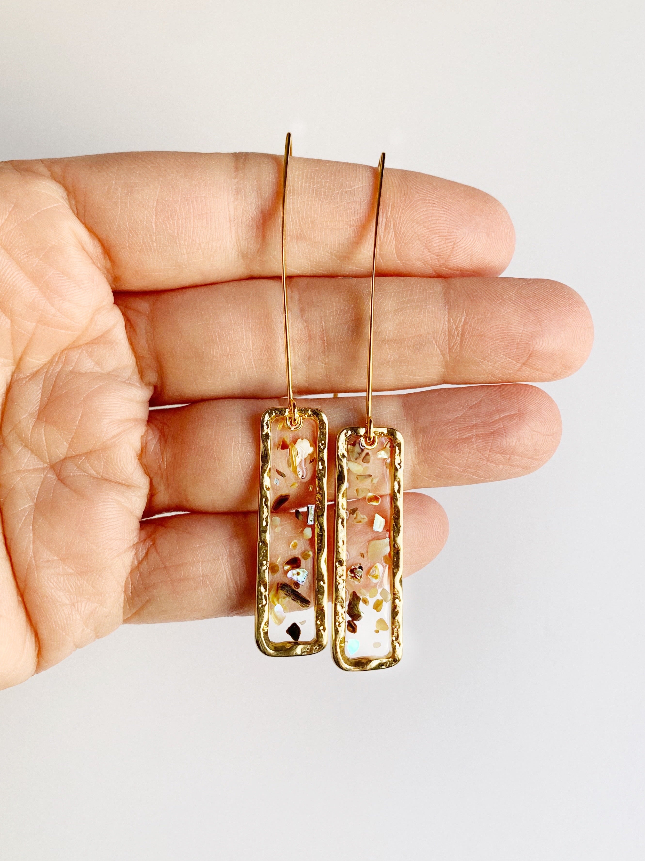 mother of pearl drop earrings being held on hand