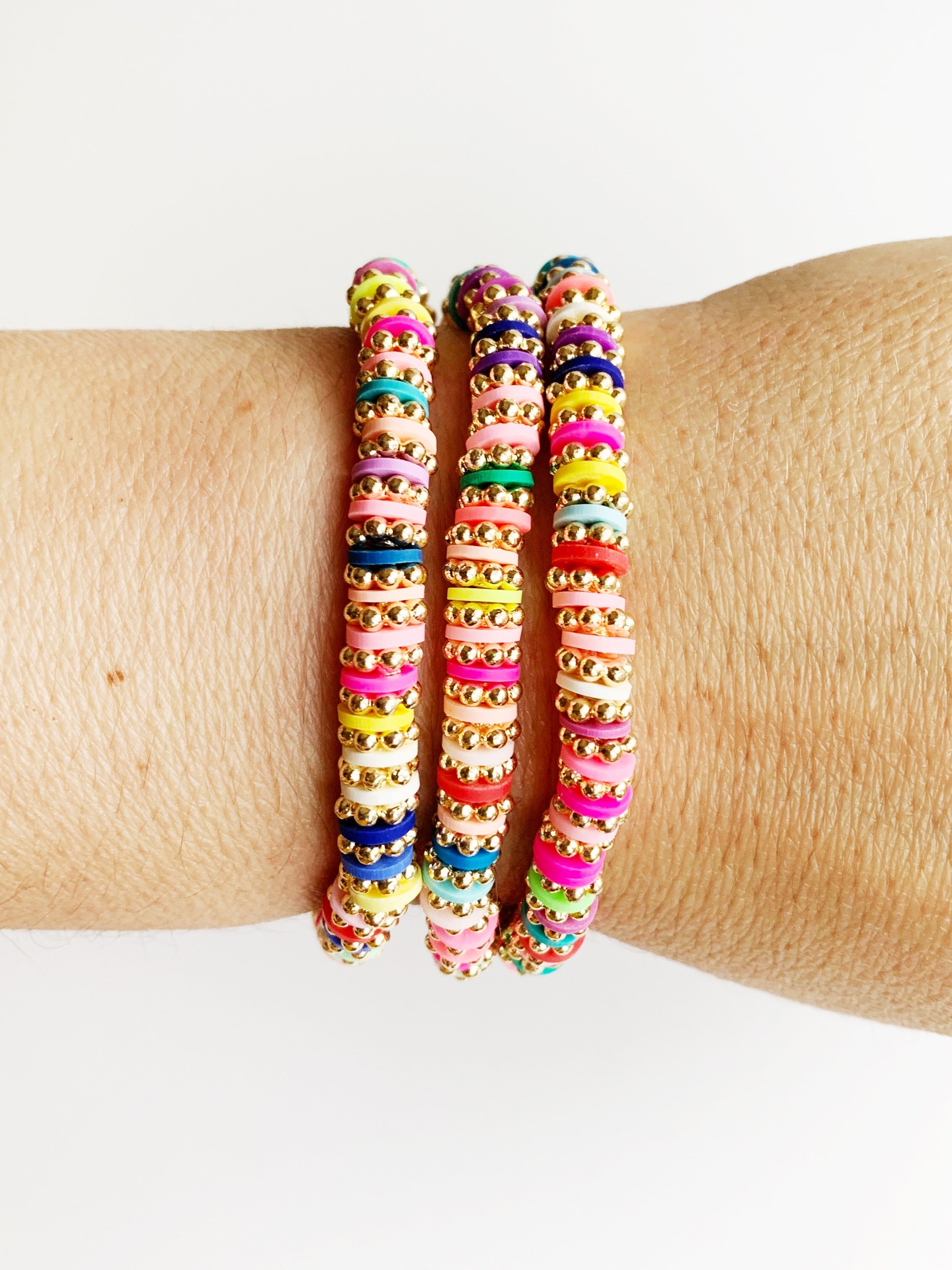 rainbow and gold stacked bracelets on wrist