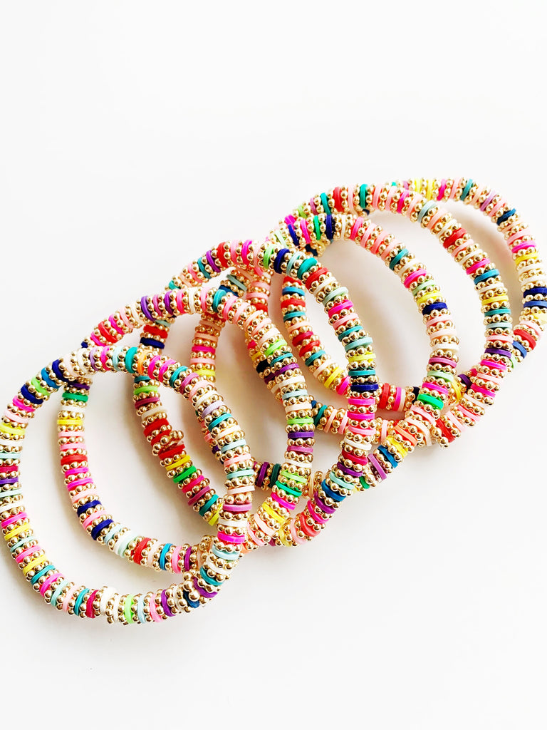 Six  Gold and Rainbow Confetti Stretch Bracelets laying together.