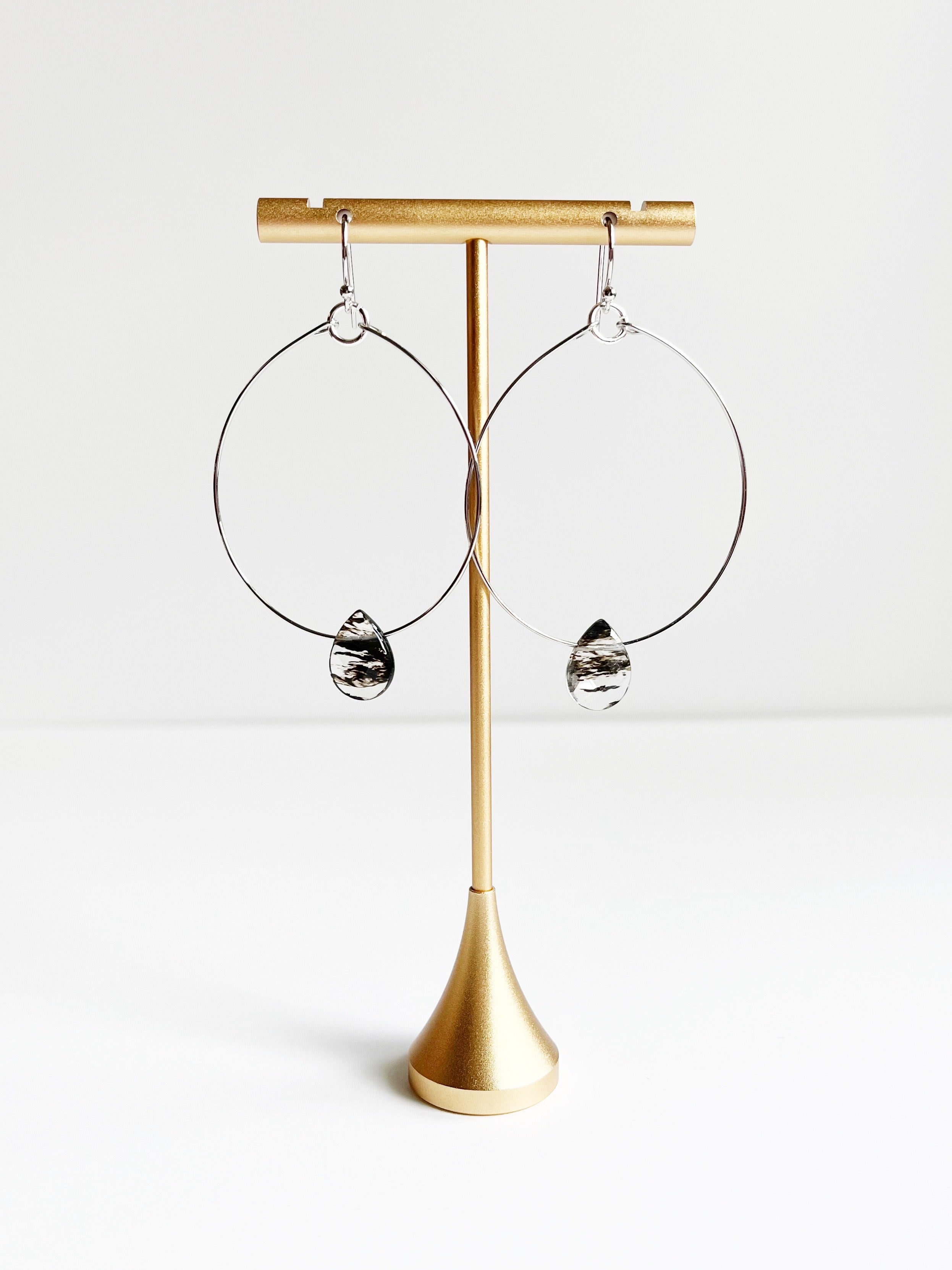 silver statement earrings displayed on gold tstand