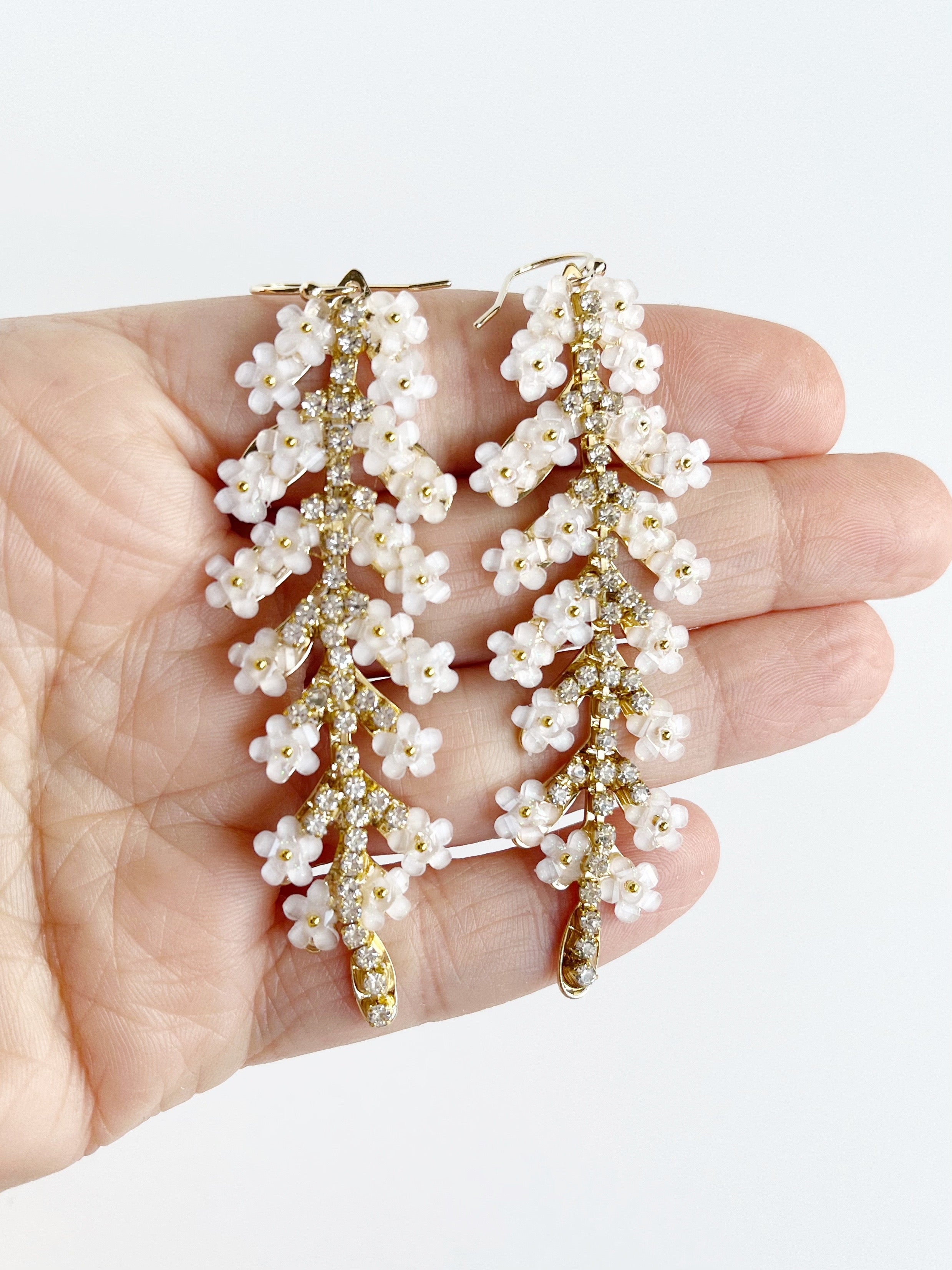 white flower dangle earrings on hand